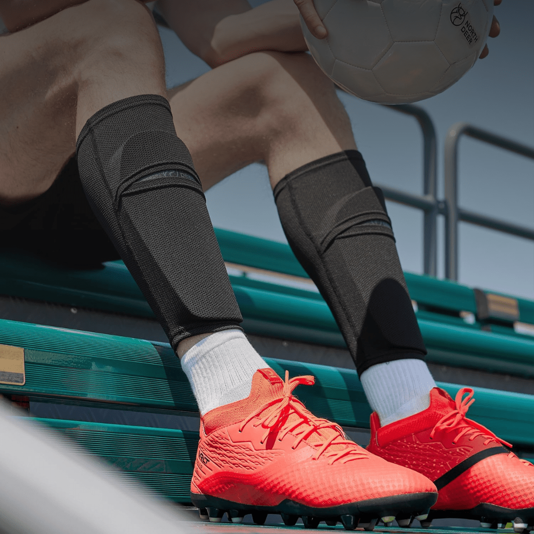 Voetballer draagt zwarte Prostec Scheenbeschermer Sleeves met hexagonale bescherming, belangrijke voetbalaccessoires