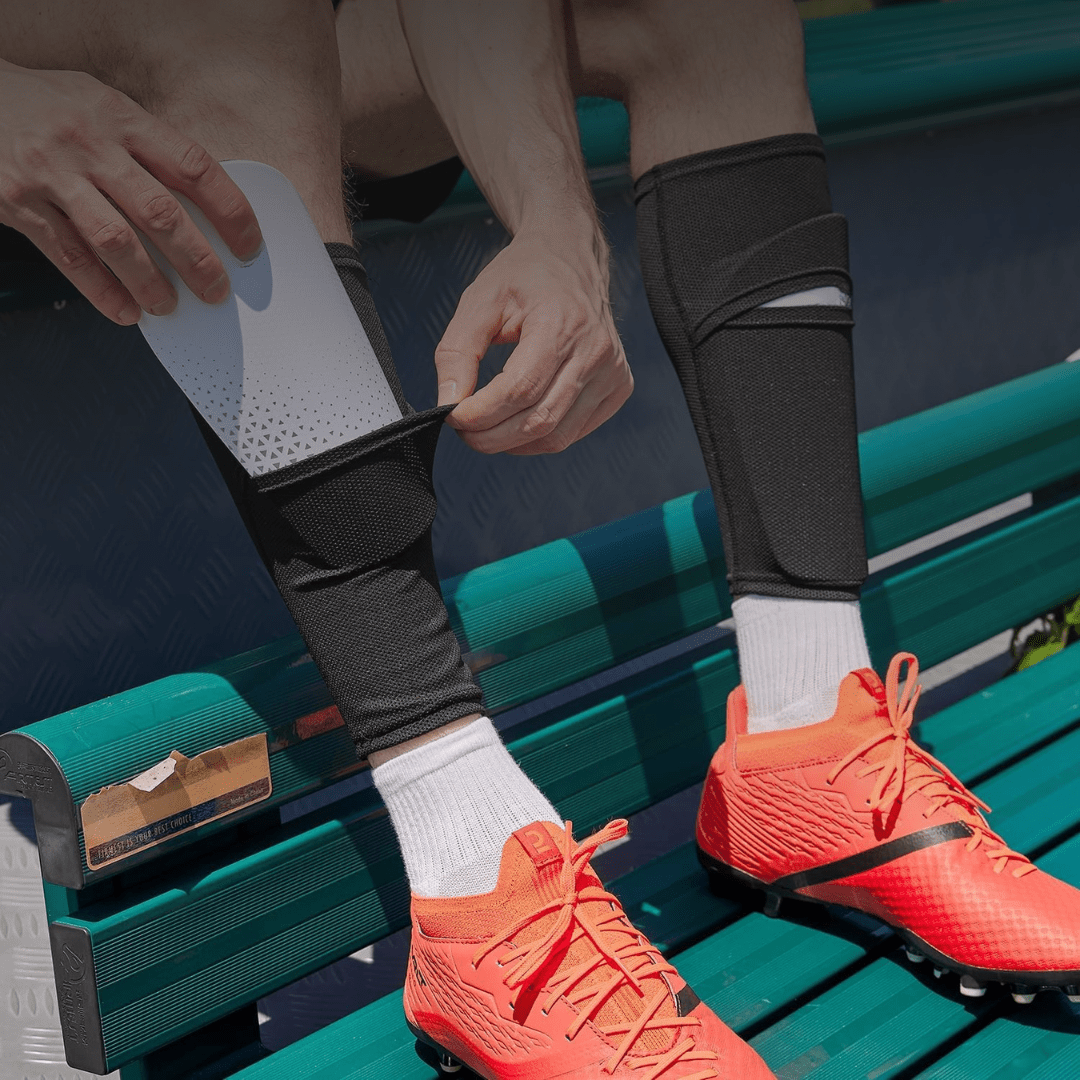 Speler stopt witte scheenbeschermer in zwarte Prostec Scheenbeschermer Sleeve, onmisbaar voetbalaccessoire